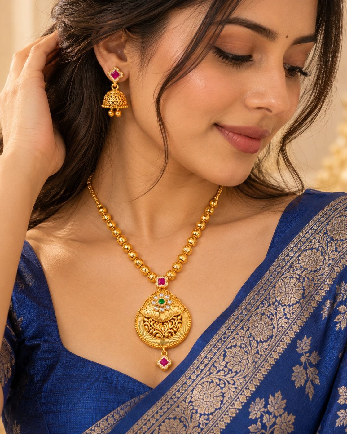 An imitation gold pendant necklace with a blue silk saree
